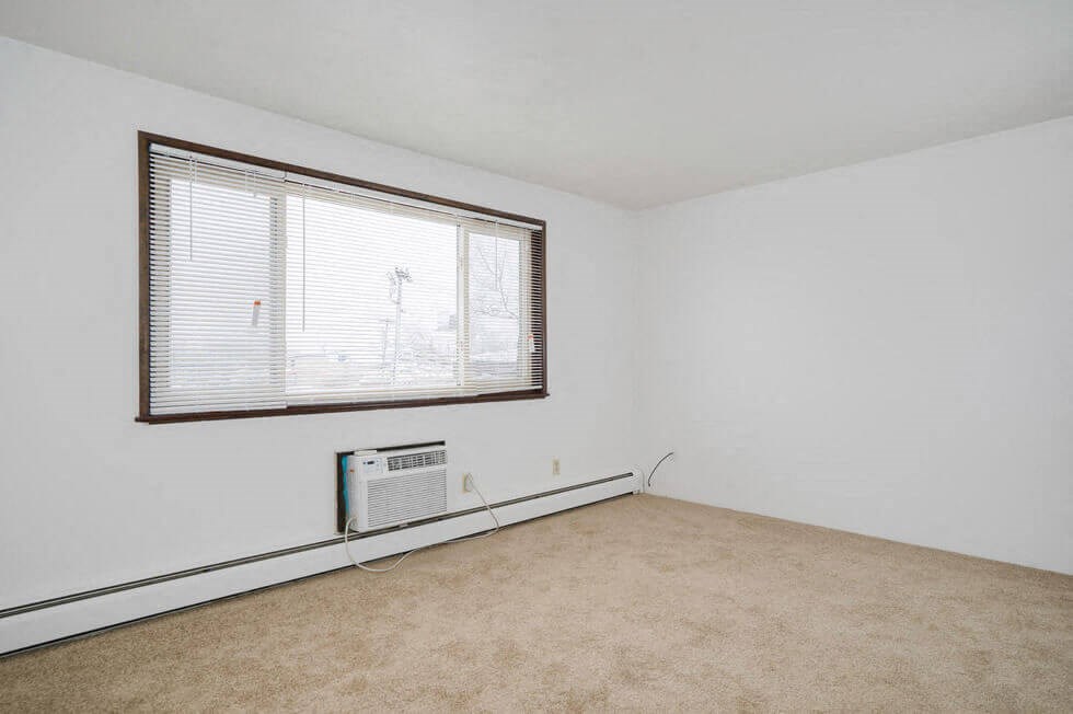 an empty room with a window and a heater