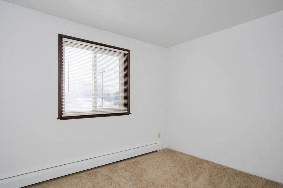 an empty room with a window and white walls