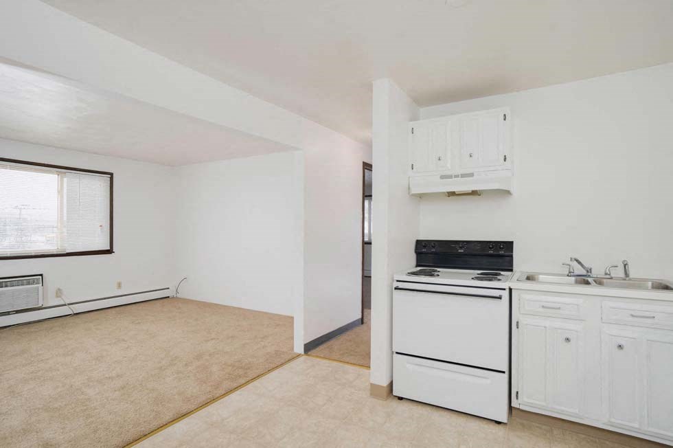 an empty kitchen with white cabinets and a stove top oven