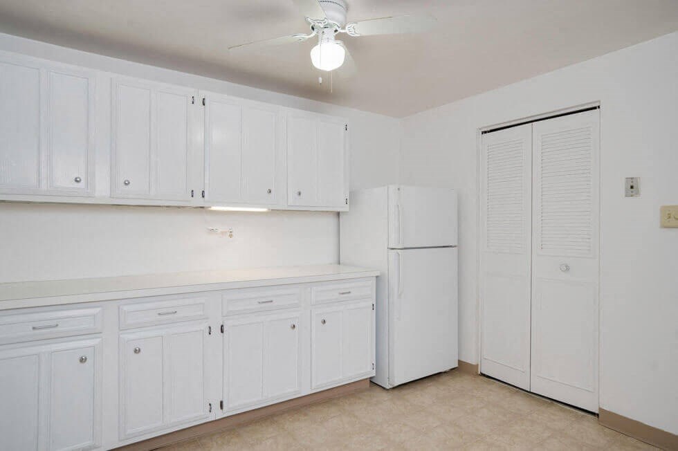 a white kitchen with white cabinets and a white refrigerator