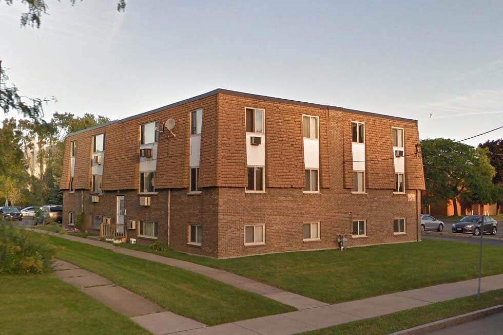 a brick building with windows on the side of a street