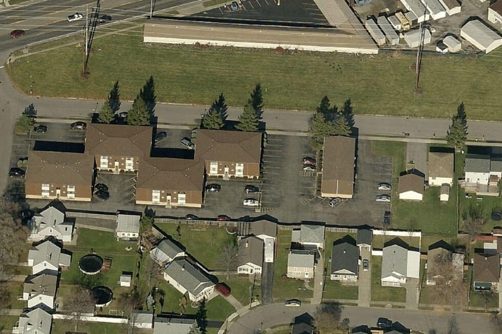 an aerial view of a neighborhood of houses with cars parked on the street