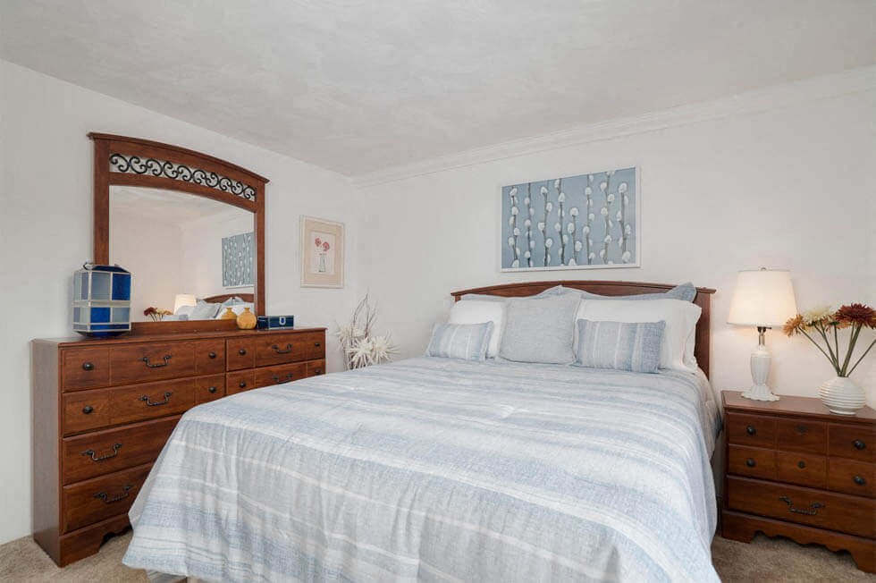 a bedroom with a bed and a dresser and a mirror