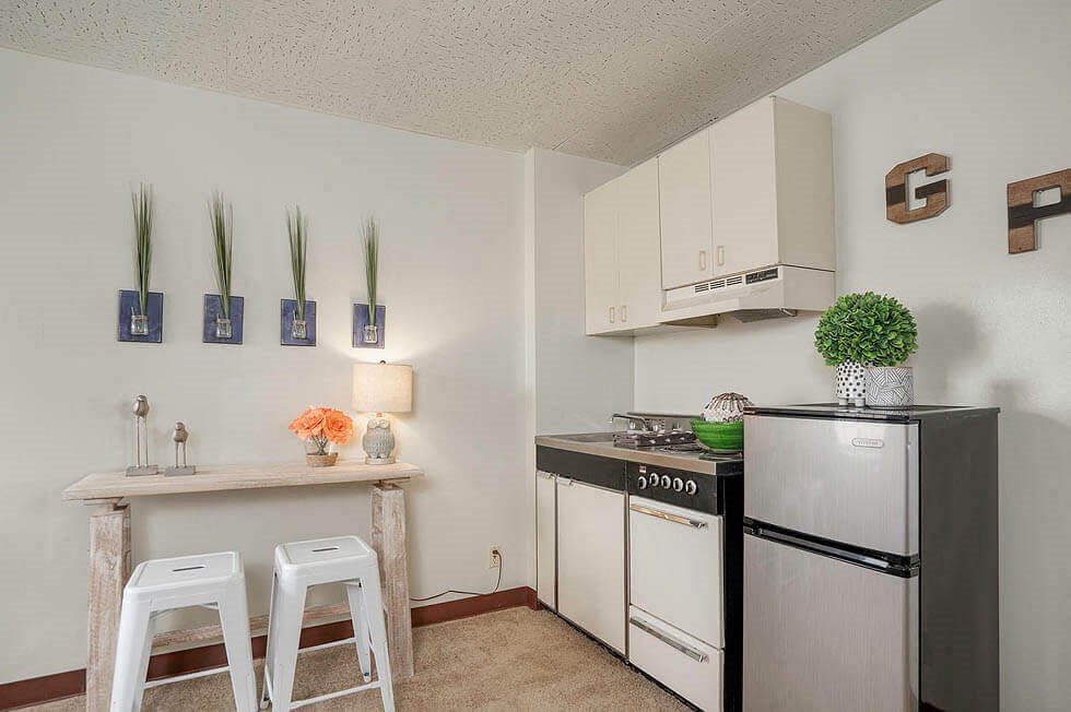 a kitchen with a refrigerator and a counter with two bar stools
