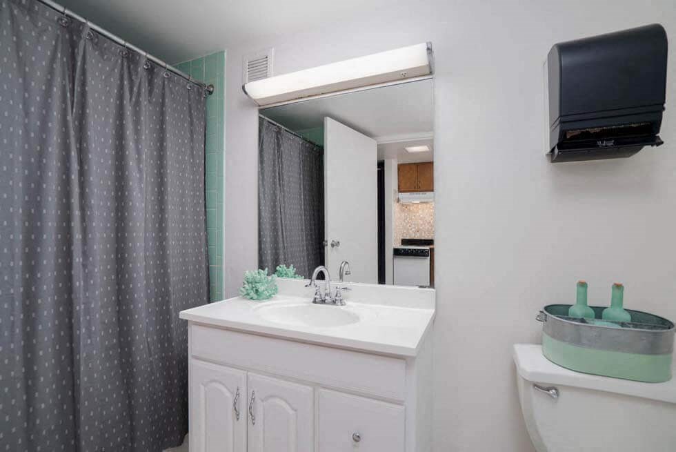 a bathroom with a sink and a mirror and a tv