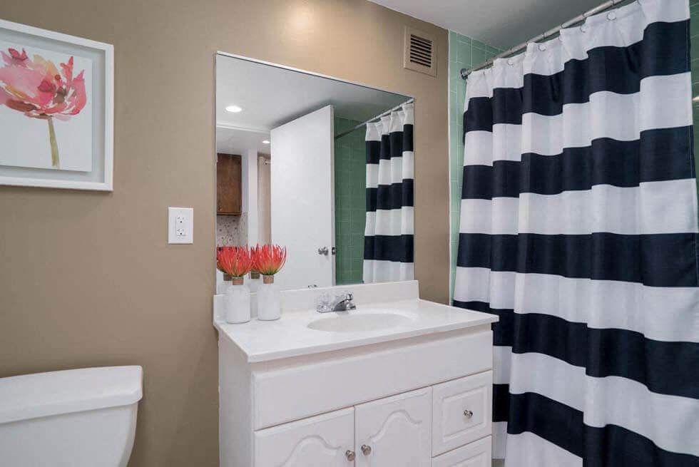 a bathroom with a white sink and a black and white shower curtain