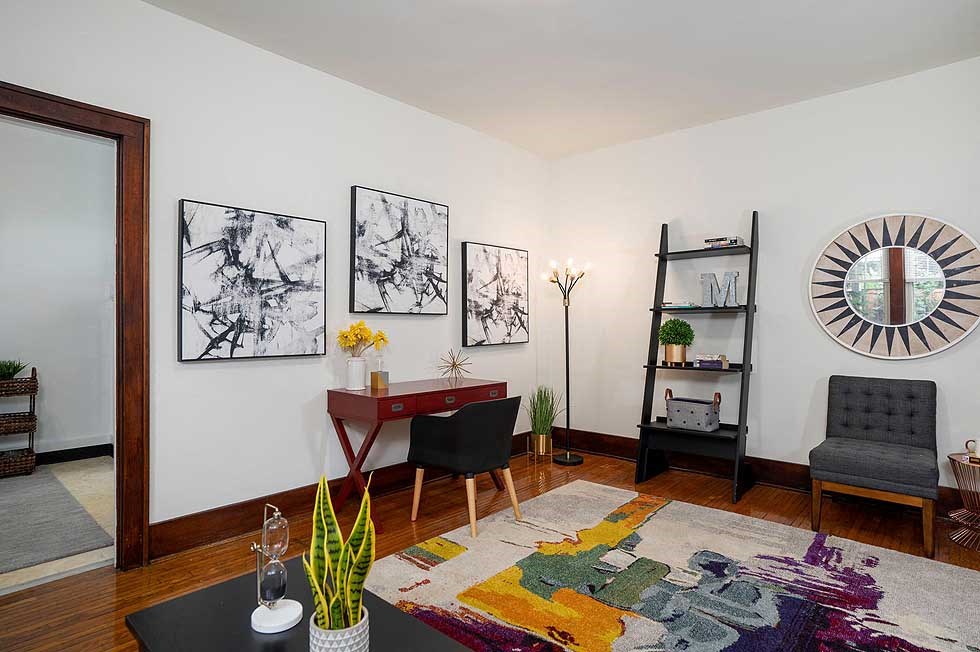 a living room with a desk and a mirror on the wall
