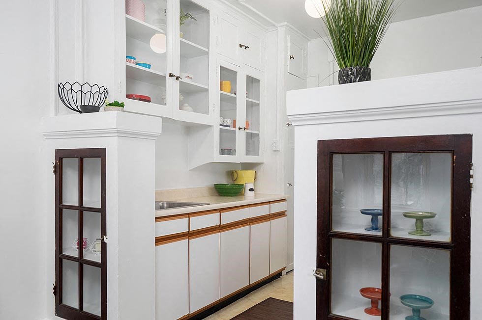 a small kitchen with white cabinets and a door