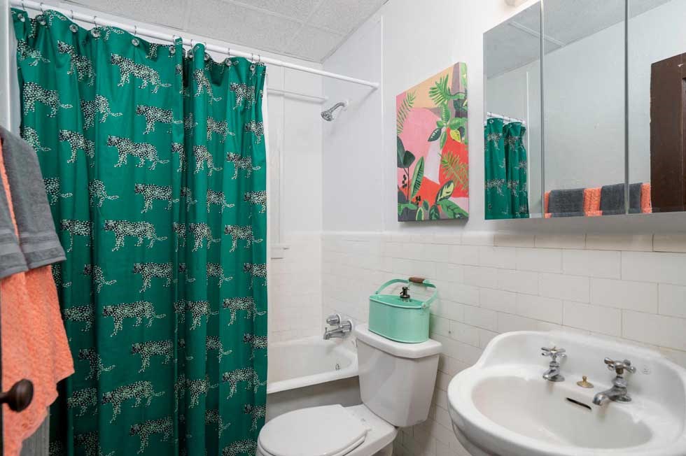 a bathroom with a green shower curtain and a toilet and sink