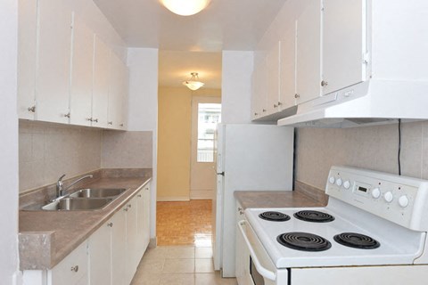 an empty kitchen with white appliances and white cabinets