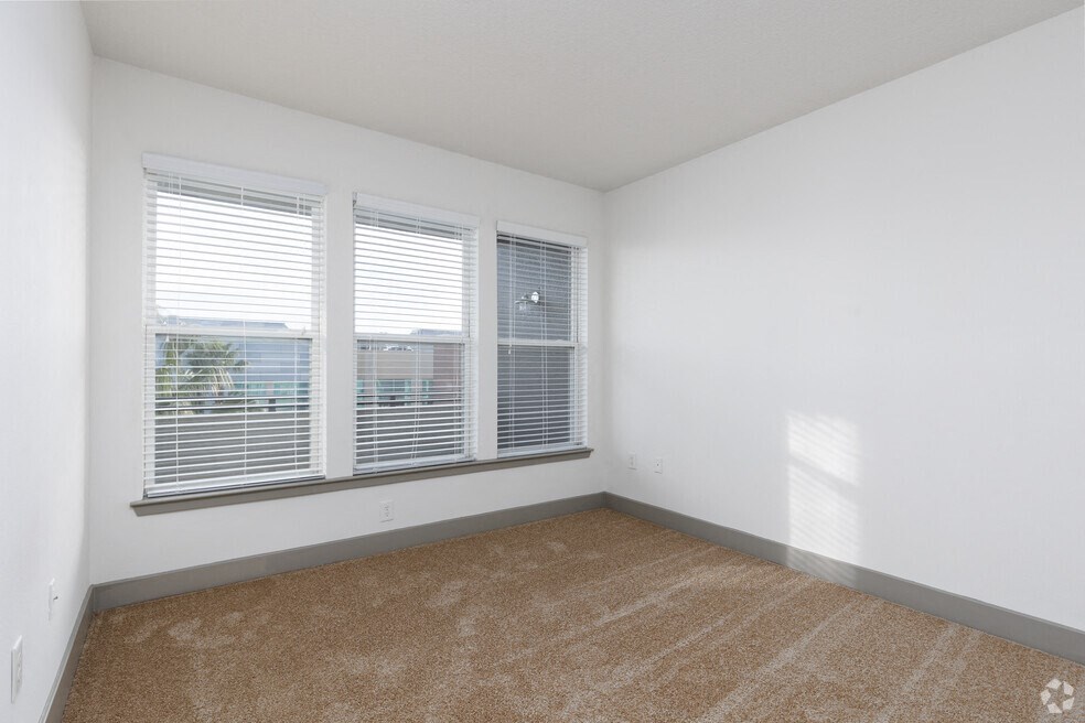 an empty room with three windows and a carpeted floor