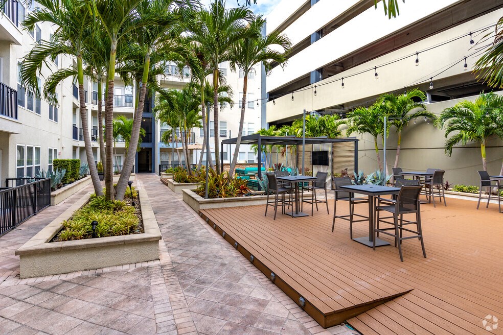 a patio with tables and chairs and palm trees