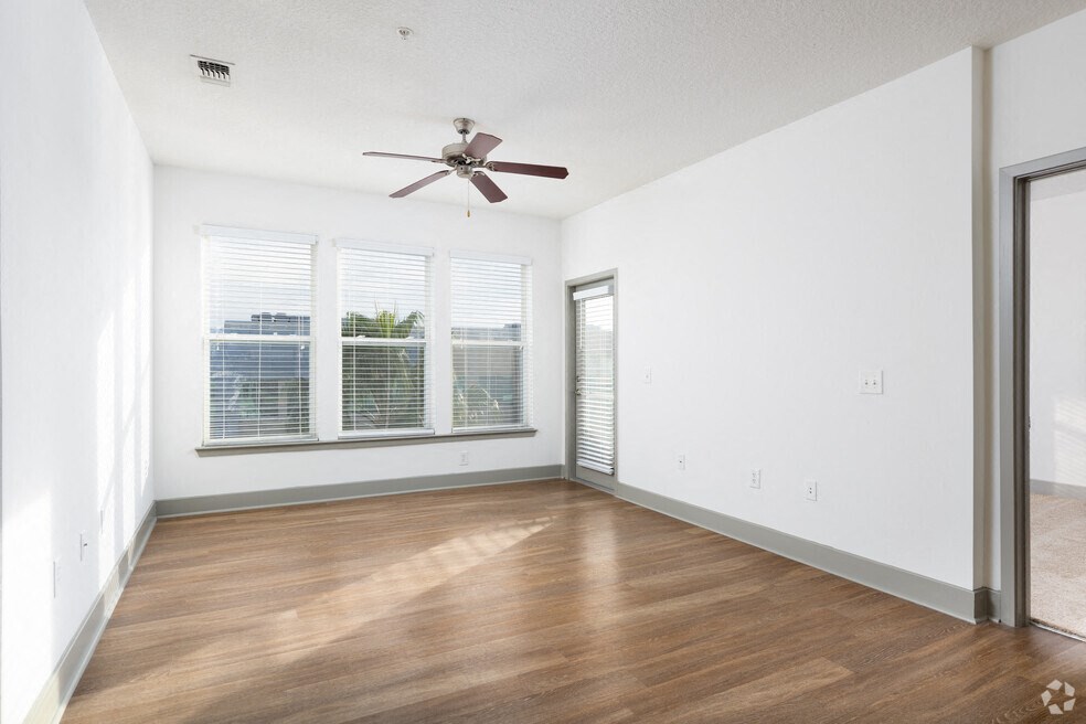 an empty living room with a ceiling fan and a window