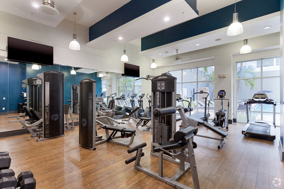a gym with cardio machines and weights on a wooden floor