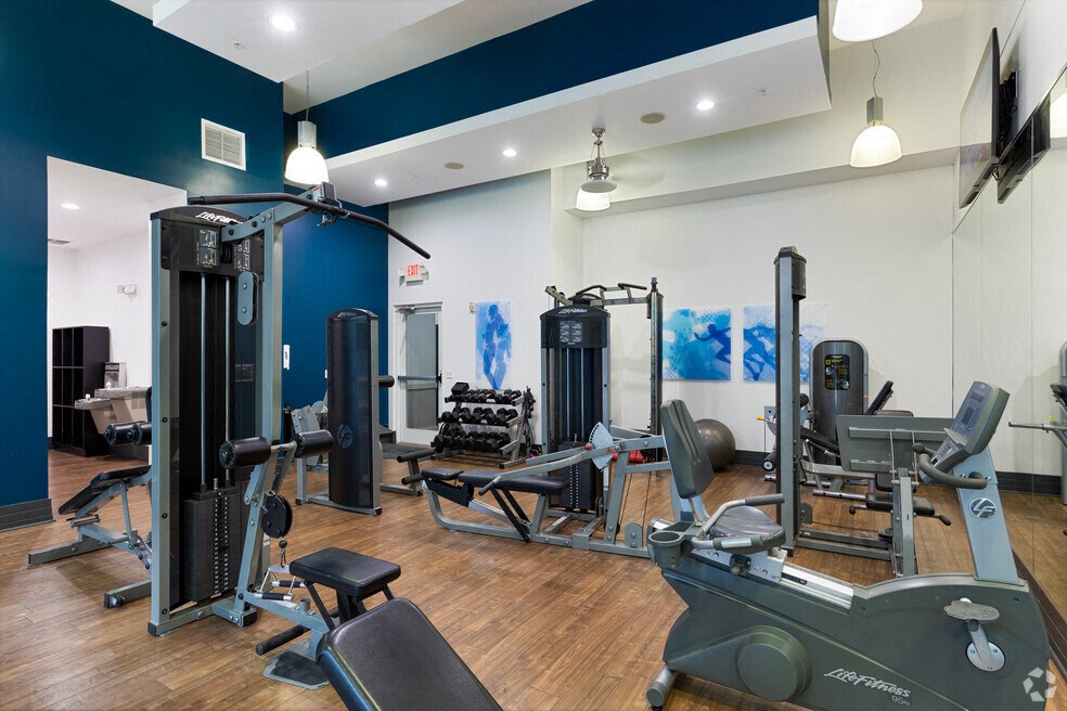 a gym with cardio equipment and weights in a building with blue walls