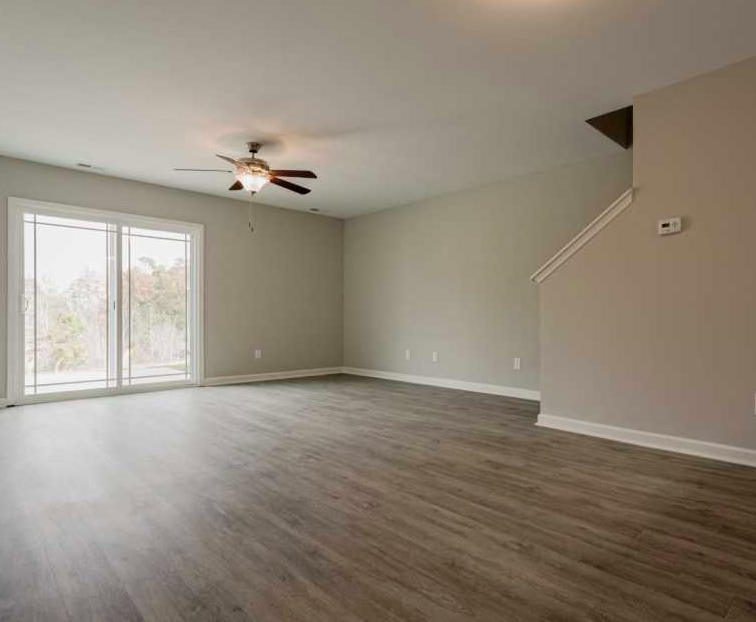 an empty living room with a ceiling fan