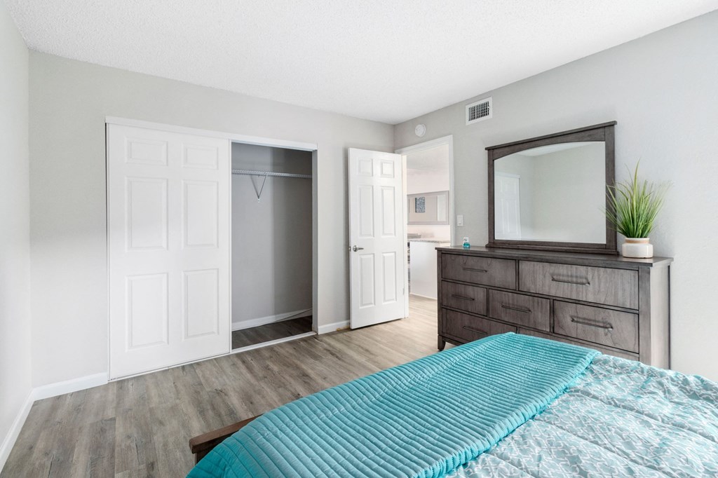 A bedroom with a bed, dresser, and mirror.