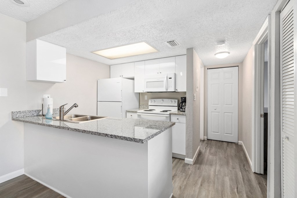 A kitchen with white cabinets and a granite countertop.