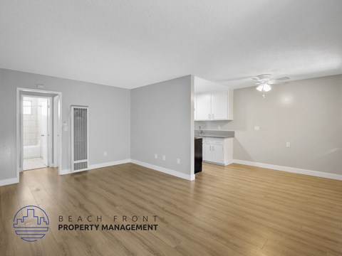 A spacious room with wooden flooring and a logo for Beach Front Property Management.
