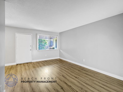 A room with wooden flooring and a window with bars on it.