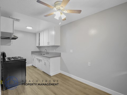 A kitchen with a stove top oven and a fan on the ceiling.