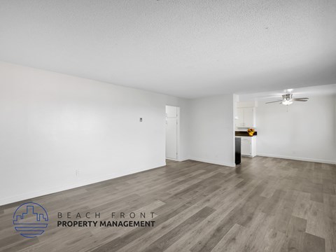 A spacious room with wooden flooring and a ceiling fan, managed by Beach Front Property Management.