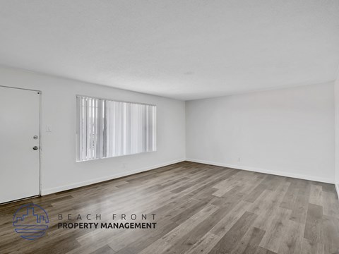 A room with wooden flooring and a window with blinds.