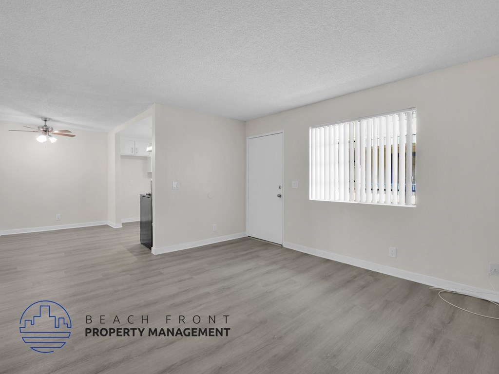 A spacious room with a ceiling fan and a window with blinds.