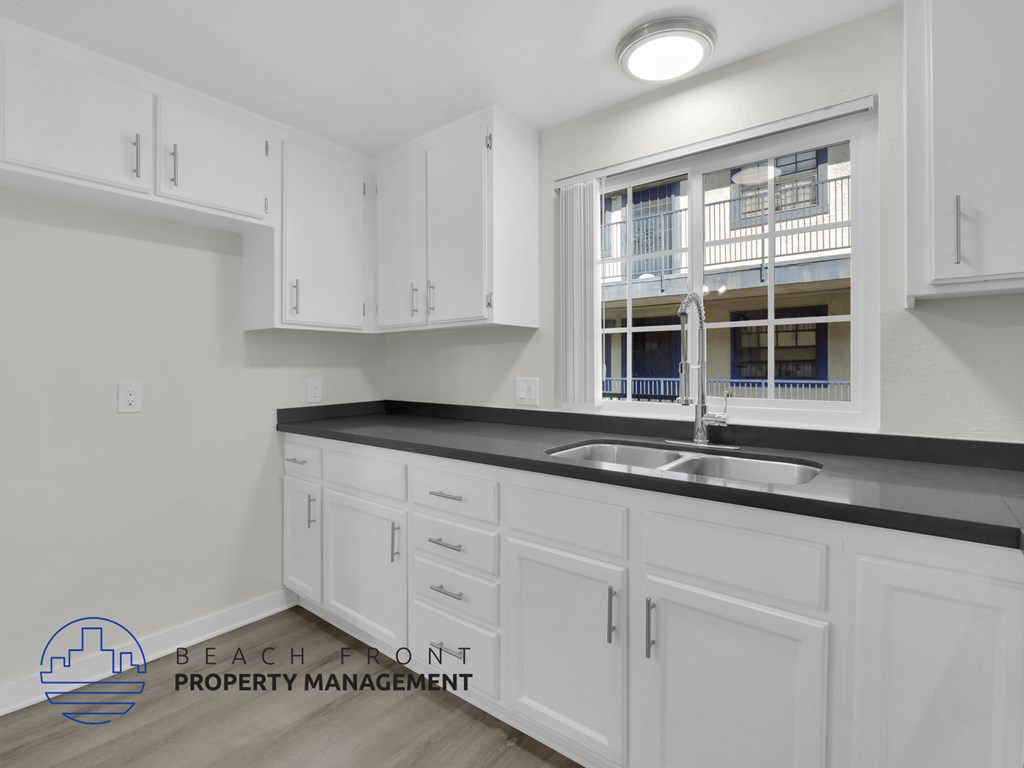 A kitchen with white cabinets and a black countertop.