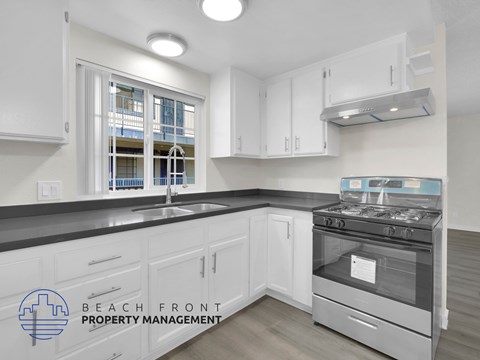 A kitchen with a stove top oven and a window with a view of a balcony.