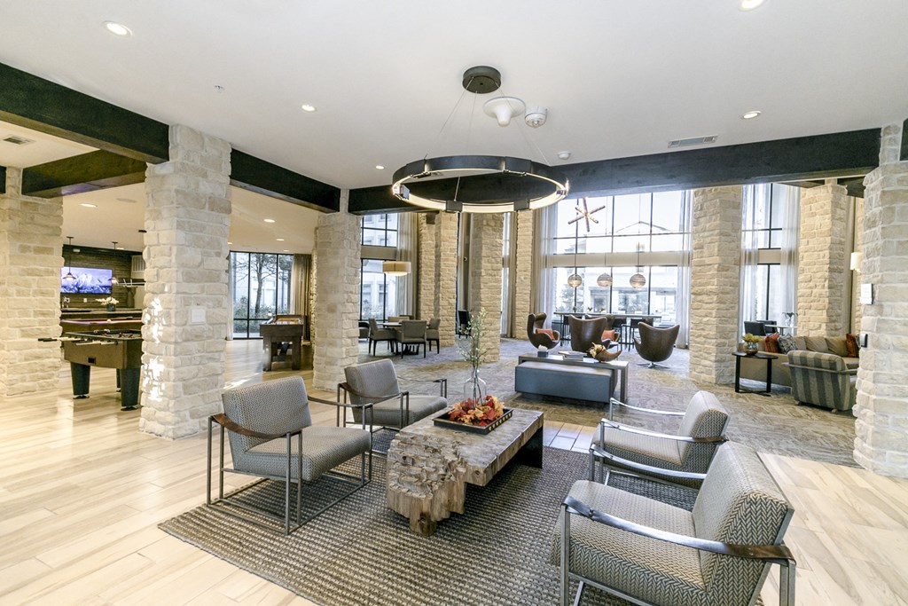 the lobby of a hotel with a large living room and a table with chairs