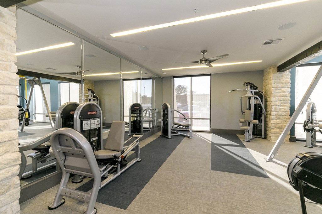 a gym with weights and cardio equipment in a building with large windows