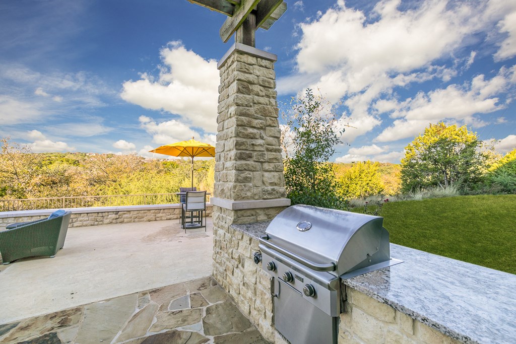 the backyard has an outdoor kitchen with a grill and an umbrella