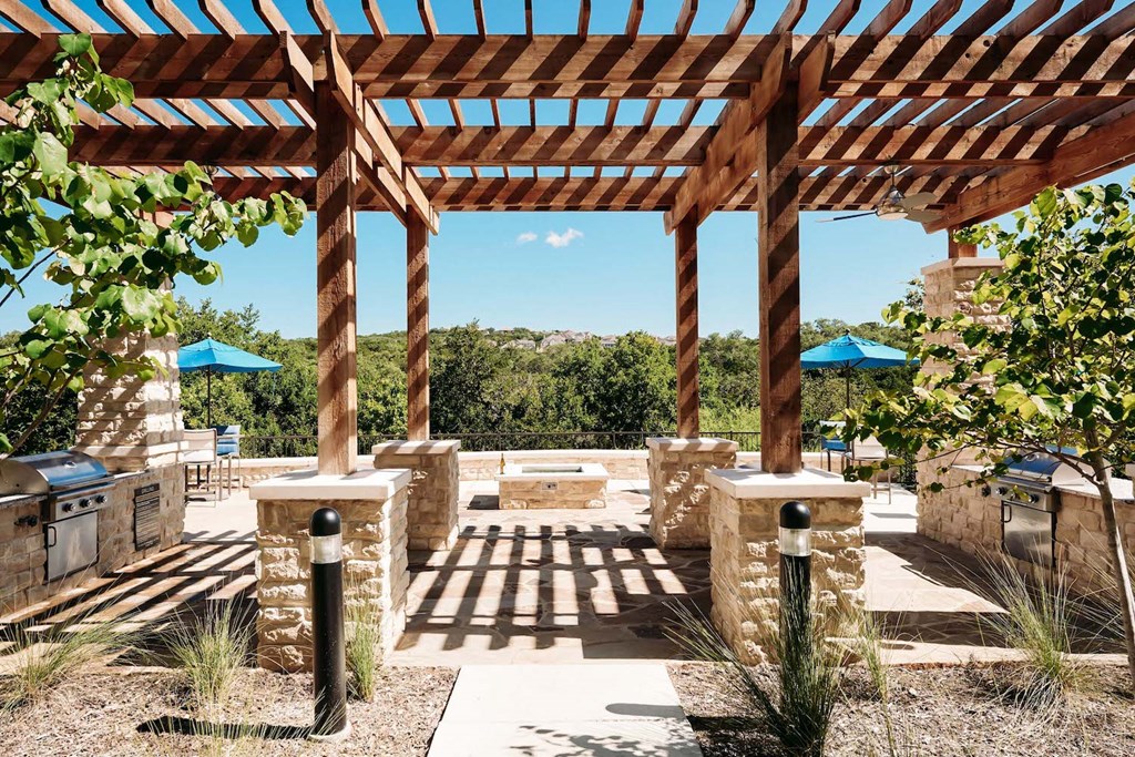 a pergola with stone columns and a courtyard with a fountain