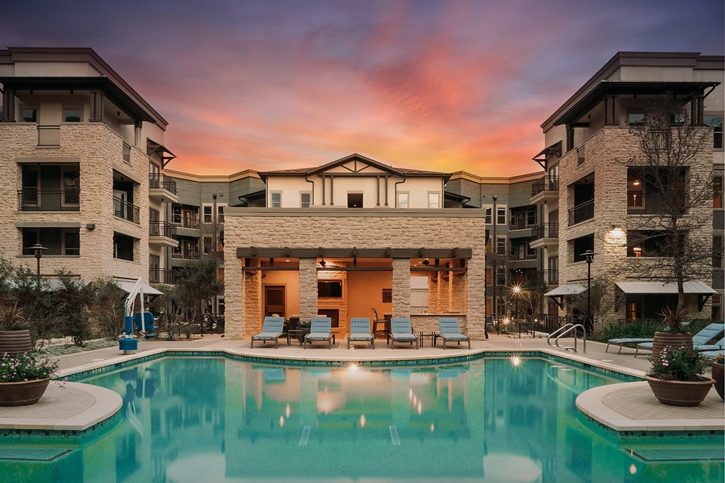 a swimming pool in front of an apartment building at sunset