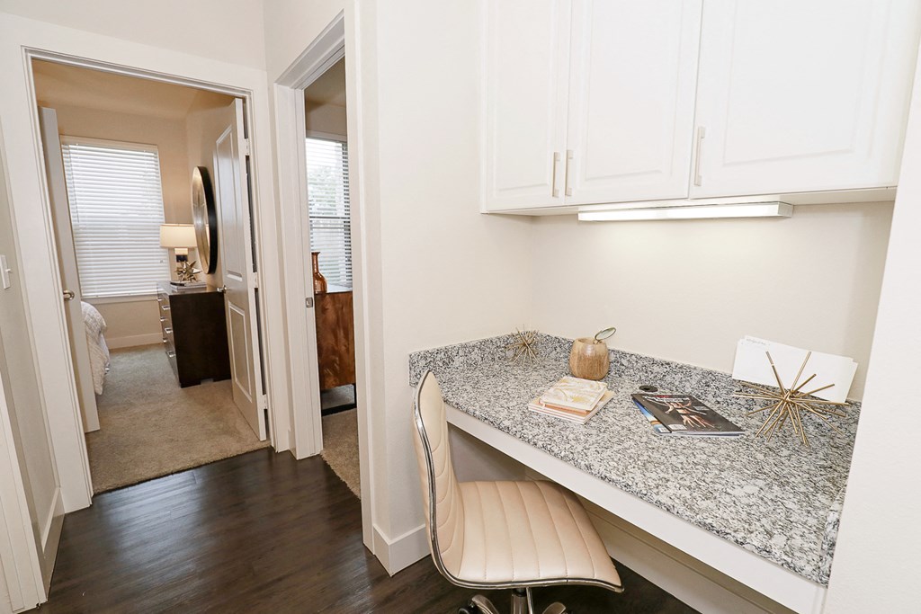 a room with a desk and a chair and a hallway with a bedroom