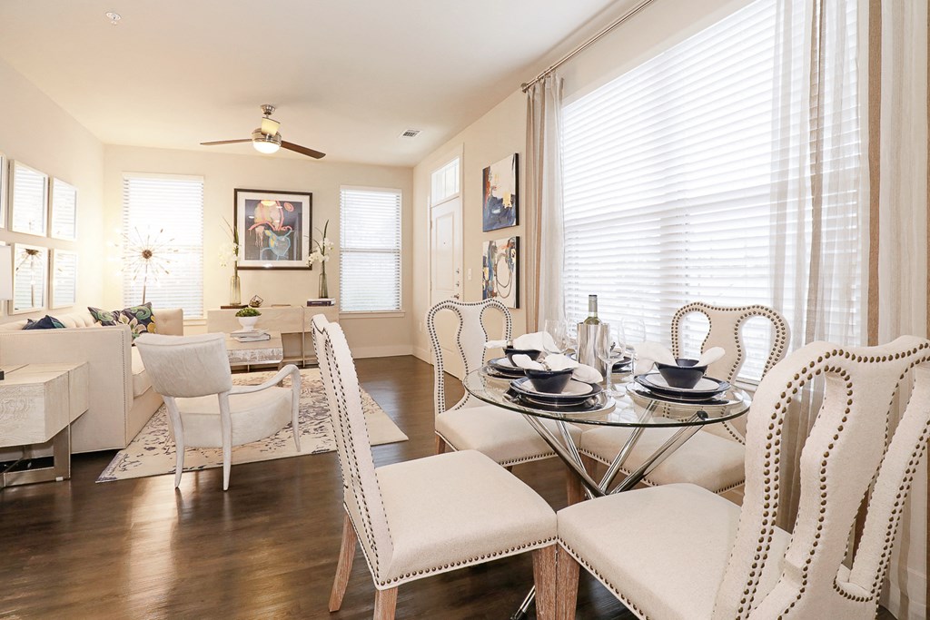 a living room and dining room with white chairs and a glass table