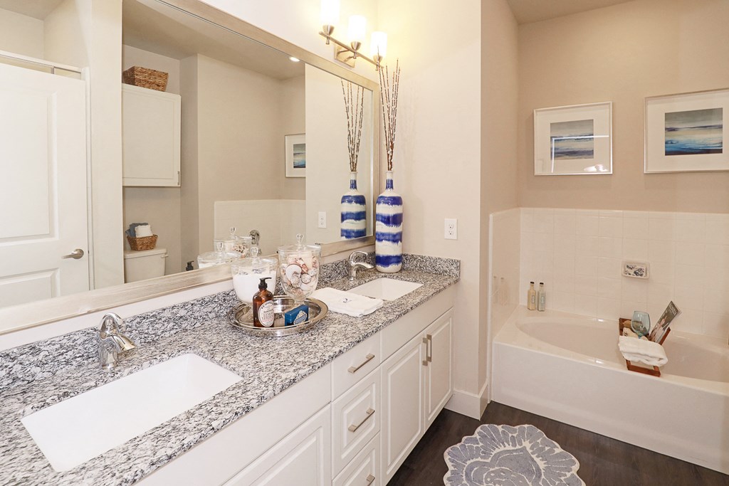 a bathroom with granite counter tops and a tub and sink