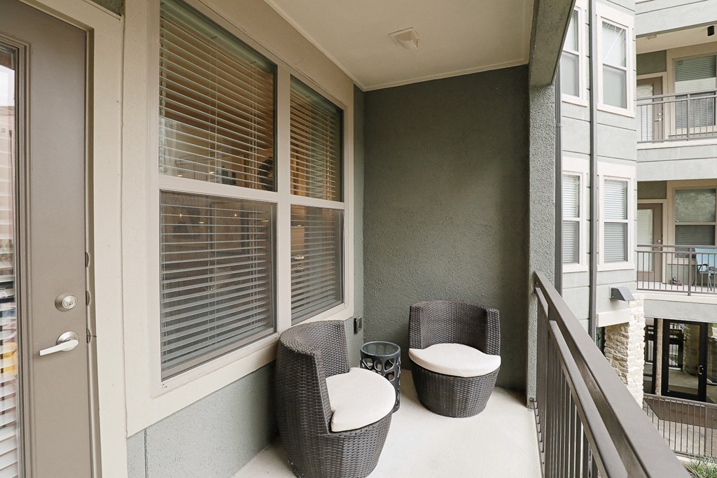 a balcony with two chairs and a table and a large window