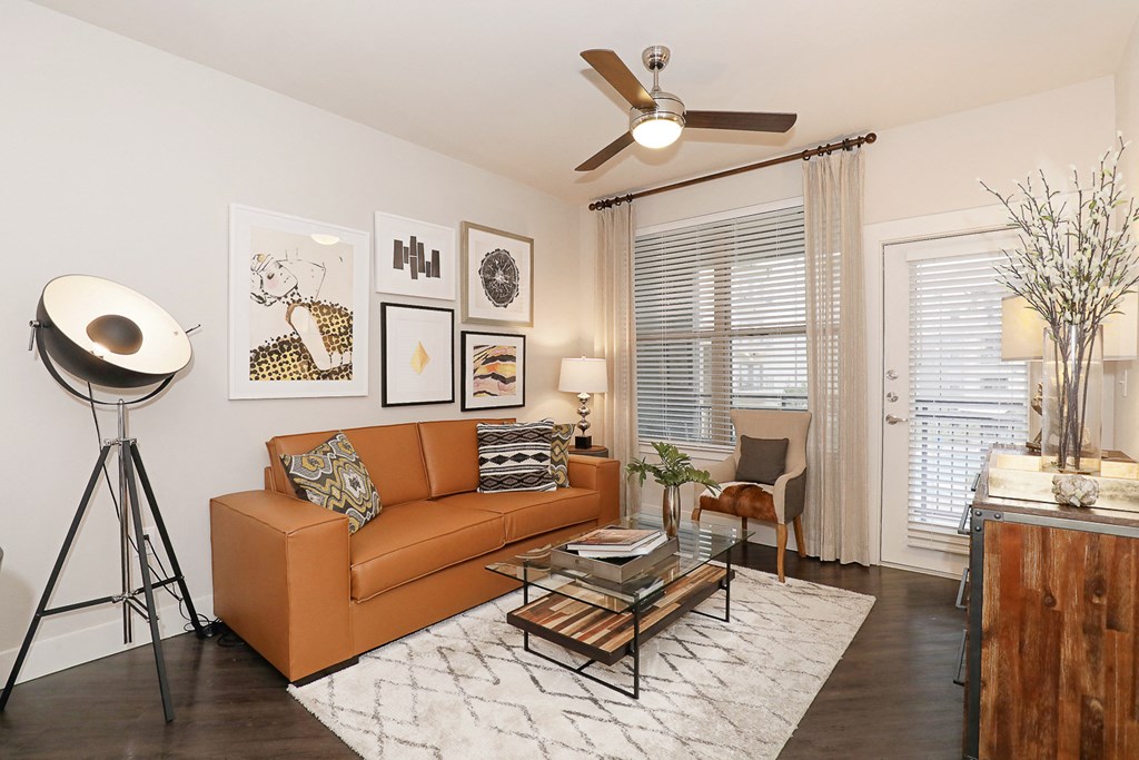 a living room with a brown couch and a ceiling fan