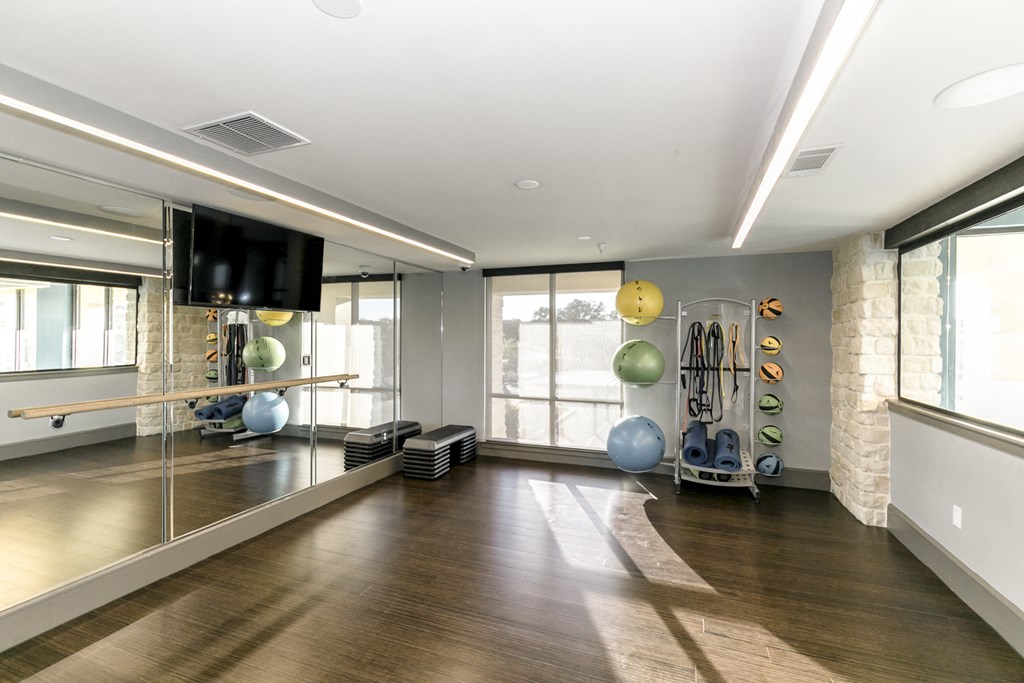 a workout room with a tv and exercise equipment in a building with large windows