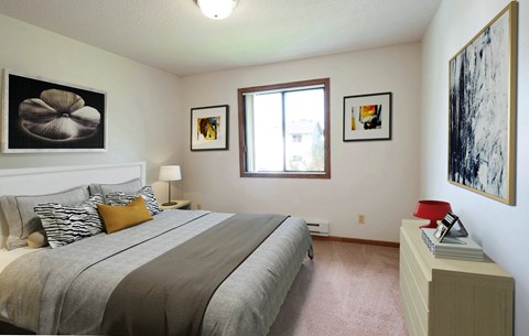 A bedroom with a large bed and two pictures on the wall.