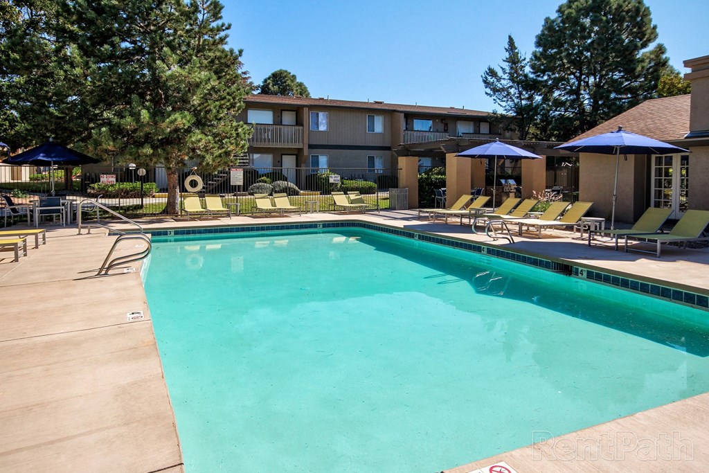 a swimming pool with chairs and umbrellas in front of a building