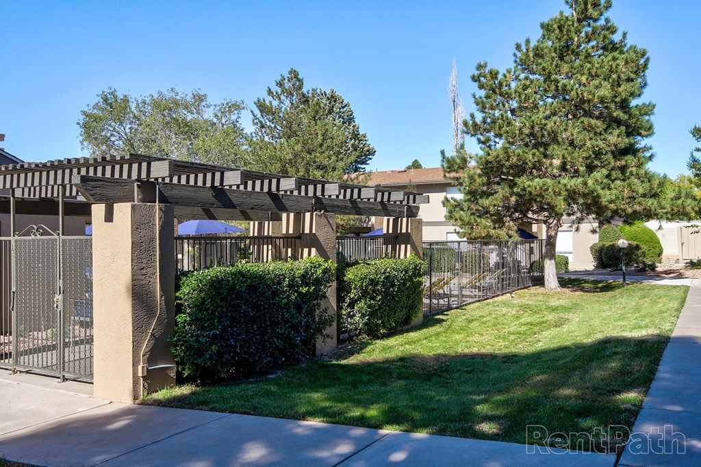 an apartment building with a fence and a lawn and trees
