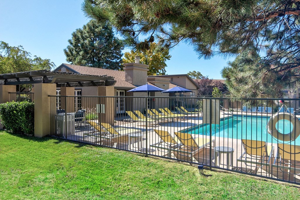 a swimming pool with lounge chairs behind a fence