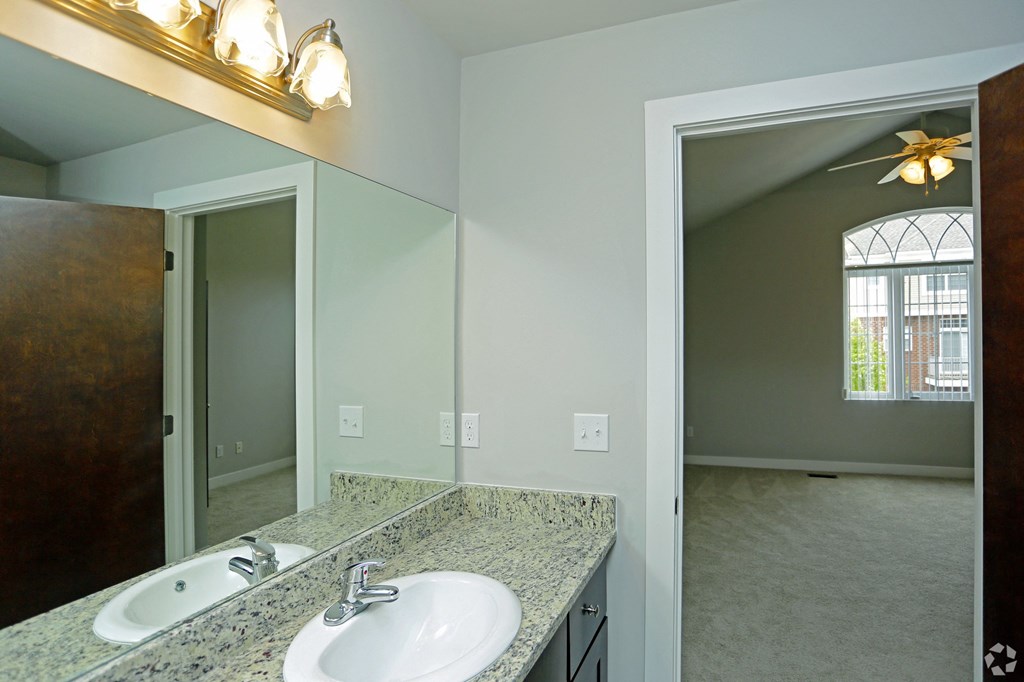 an empty bathroom with a sink and a large mirror