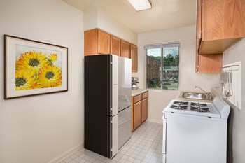kitchen at Bedford Station apartments in Hyattsvile MD with tile flooring, wood cabinets, tan countertops and a painting of yellow flowers - Photo Gallery 3
