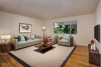 living room at Bedford Station apartments in Hyattsville MD with couch, chairs, coffee table, mounted TV, credenza, floor lamp and side table - Photo Gallery 4