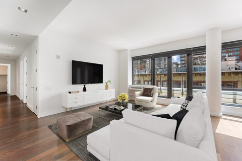 A modern living room with a white couch and a flat screen TV mounted on the wall.