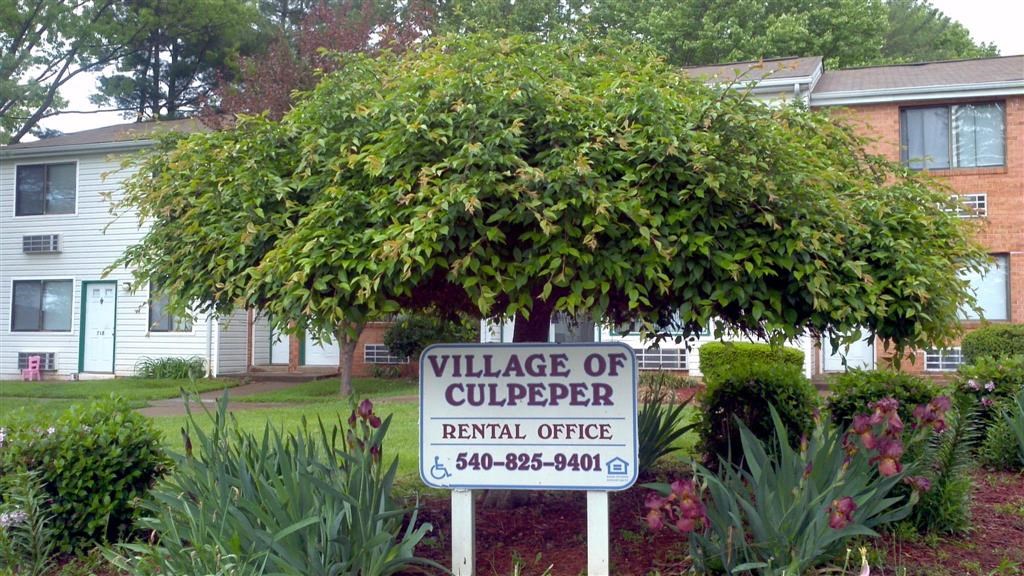 a sign for the village of copper rental office in front of a tree
